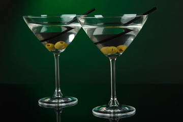 Martini glasses with olives on dark green background