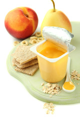Tasty yogurt in open plastic cup, cookies and fruit,