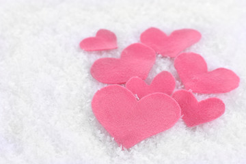 Little felt hearts on snowy background