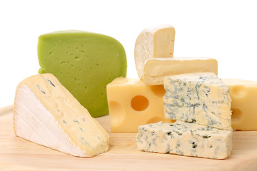 Various cheese on wooden plate.