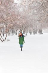 Fototapeta na wymiar Pretty girl in green overcoat walks outdoor at winter day