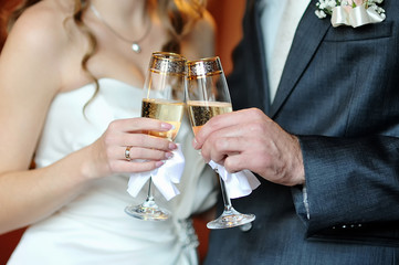 closeup hands of the bride and groom with glasses of champagne