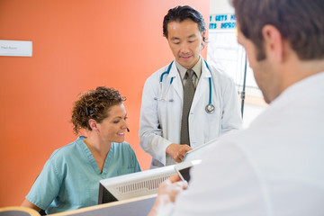 Medical Team Using Digital Tablet While Patient Standing At Rece