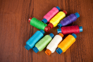 colorful spools of thread on a wooden background