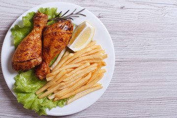 Two fried chicken drumsticks with french fries.  top view