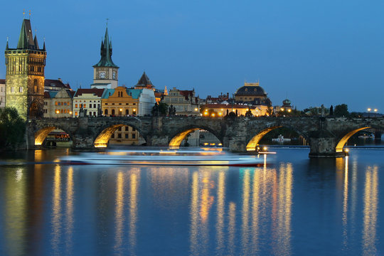 Charles bridge in the evening, cityscape with sailing boat