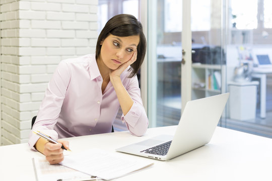 Depressed businesswoman sitting in office behind her laptop