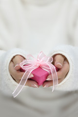 Hands with white long sleeves holding gift wrapped box