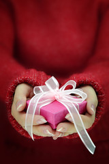 Female hands with long sleeves holding gift box