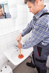 Plumber Pressing Plunger In Sink