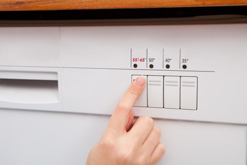 Woman Pressing Button Of Dishwasher