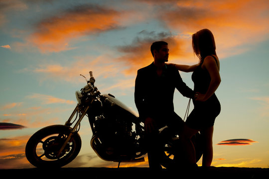 silhouette of woman by man on motorcycle