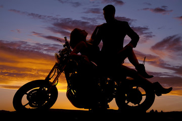Fototapeta na wymiar woman lay back on motorcycle man stand silhouette