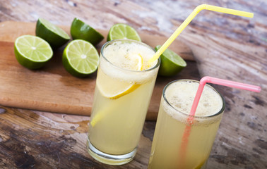Fresh limes and lemonade on wooden background