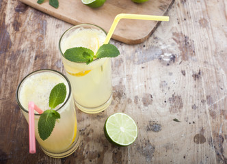 Fresh limes and lemonade on wooden background