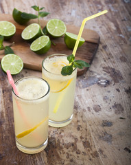 Fresh limes and lemonade on wooden background