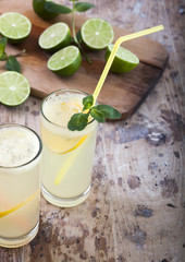 Fresh limes and lemonade on wooden background