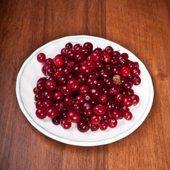cranberries on a saucer on a wooden background