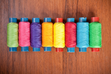 colorful spools of thread on a wooden background
