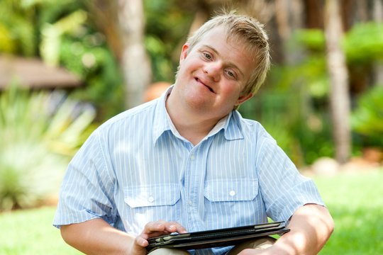 Boy wih down syndrome playing on tablet.