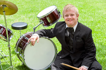 Young handicapped drummer next to drums.