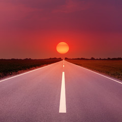 Driving on an empty highway towards the setting sun