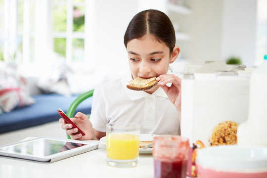 Schoolgirl With Digital Tablet And Mobile Eating Toast