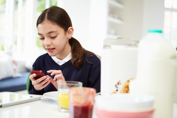 Obraz na płótnie Canvas Schoolgirl With Digital Tablet And Mobile At Breakfast