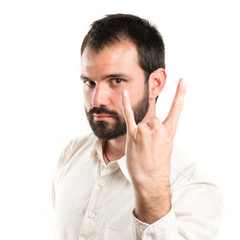 Young man doing the horn sign over white background