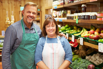 Two Sales Assistant At Vegetable Counter Of Farm Shop