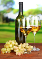 Ripe grapes, bottle and glasses of wine, on bright background
