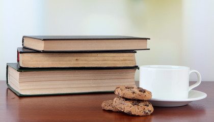 Cup of coffee with cookies and books