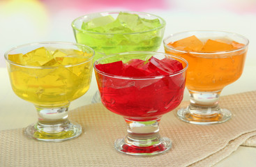 Tasty jelly cubes in bowls on table on light background