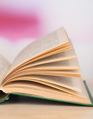 Opened book on wooden table on bright background