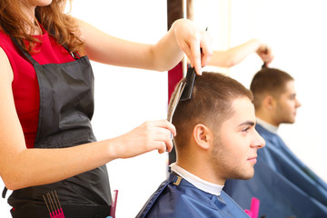 Beautiful girl hairdresser cut guy in beauty salon