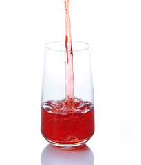 Juice pouring into glass isolated on white