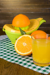 Citrus press and oranges on table on wooden background