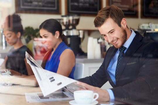 Businessman Reading Newspaper In Coffee Shop