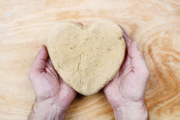 Man holding heart made of pastry in his hands