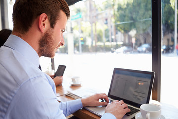 Businessman Using Laptop In Coffee Shop