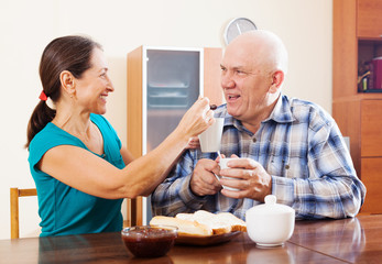 Loving mature couple having tea with jam