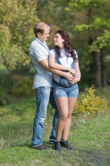 Young man with his pregnant wife posing on open air