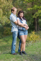 Fototapeta premium Young man with his pregnant wife posing on open air