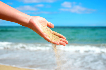 Fototapeta na wymiar Women hand pours sand on tropical beach.Travel and tourism.