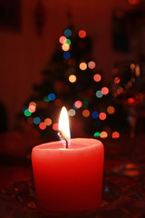 Красная свеча на фоне новогодней елки