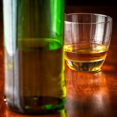 Whisky or rum and a green liquor bottle on a wooden table