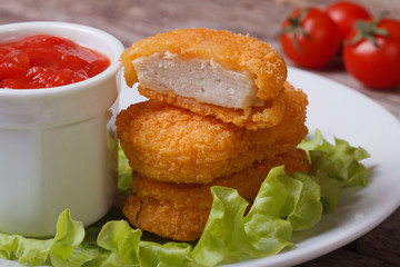 chicken nuggets, lettuce and ketchup on a plate closeup