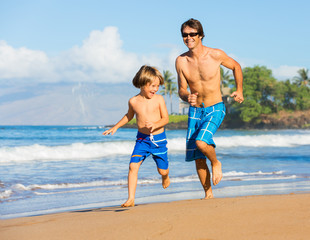 Happy father and son playing and running together at beach