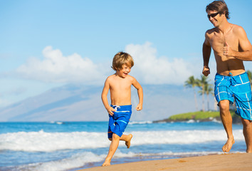 Happy father and son playing and running together at beach