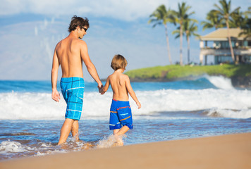 Happy father and son walking together at beach
